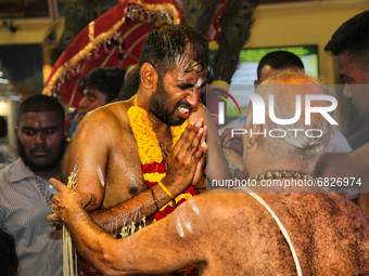 Tamil Hindu devotee receives blessings from a Hindu priest after performing the para-kavadi ritual (a ritual where he is suspended by hooks...