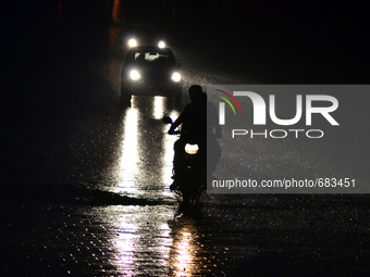 An indian motorcyclist rides on a pathway during rains in Allahabad,on July 10,2015. (