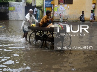 An Indian vendor transport  his child in a cart in  the waterlogged street due to heavy rain in Kolkata, India on  Friday, July 10, 2015. (