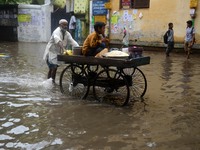 An Indian vendor transport  his child in a cart in  the waterlogged street due to heavy rain in Kolkata, India on  Friday, July 10, 2015. (