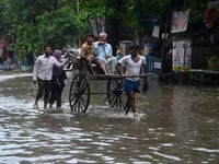 An Indian rickshaw puller transports passengers in the waterlogged street due to heavy rain in Kolkata, India on  Friday, July 10, 2015. (