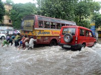 Indian street children  pushing the breakdown  bus  in the waterlogged street due to heavy rain in Kolkata, India on  Friday, July 10, 2015....