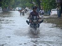 Indian young  people enjoy the bike ride  in  the waterlogged street due to heavy rain in Kolkata, India on  Friday, July 10, 2015. (