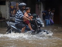 Indian school boy returning home   along  the waterlogged street due to heavy rain in Kolkata, India on  Friday, July 10, 2015. (