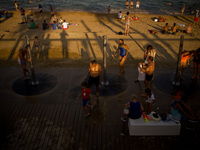 People cool in showers and sea at Barcelona beach as the sun sets on 10 July, 2015.  (
