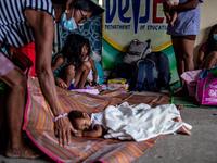 A child seeking temporary shelter at an elementary school lays on a woven mat, in Laurel, Batangas province, Philippines, on July 2, 2021. T...