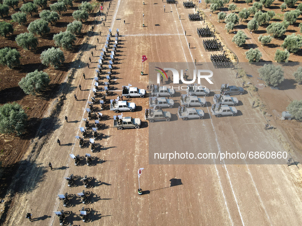 Syrian fighters march in columns, ride dirt bikes and and drive pick-up trucks during a graduation ceremony near the northern city of Afrin...