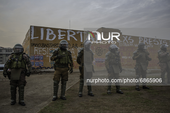 Chilean riot polices from carabineros de Chile, standing right in front of the wall with the phrase -free the prisoners-, scratched on the w...