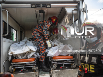 Firefighter's and rescue workers carry the bodies into an ambulance that were recovered after a fire broke out at the Hashem Foods Ltd at Ru...