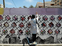 Palestinian artists take part in an event as they draw murals and hang pictures of children who killed during the recent Israeli military es...