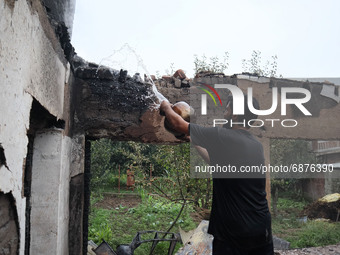 A Kashmiri resident tries to douse fire inside a damaged residential house where three militants were killed in a military operation in Newa...