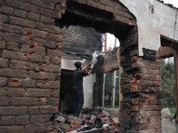 A Kashmiri resident tries to douse fire inside a damaged residential house where three militants were killed in a military operation in Newa...