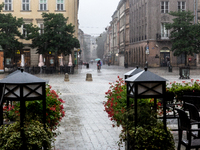 Passers-by walk in heavy rain on inundated streets on the Main Market Square in Krakow, Poland as another wave of extreme torrential rains a...