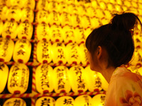 Visitors walk past paper lanterns bearing the names of individuals and companies who contributed to the shrine during the Mitama Festival at...