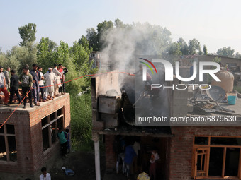 Kashmiri People try to douse the fire at a damaged residential house where two Militants were killed in a military operation in Srinagar, In...