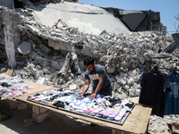 A Palestinian street vendor sells clothes near the rubble of al-Shuruq tower in Gaza City's al-Rimal neighbourhood which was targeted by Isr...