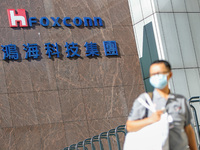 A man with a face mask walks past the  logo of Foxconn, or Hon Hai Group , which is Taiwan’s technology giant and the world’s leading produc...