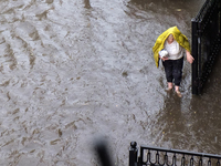 A woman walks down a flooded street during a heavy downpour in Kyiv, Ukraine. July 19, 2021  (