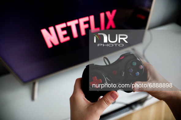 Netflix logo displayed on a tv screen and a gamepad are seen this illustration photo taken in Krakow, Poland on July 19, 2021. 