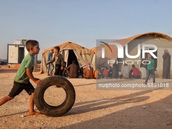 A Syrian child plays with a car tire in front of a mosque in a camp near the town of Maarat Misrin in the northern countryside of Idlib gove...