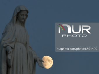 View of the moon and the statue of the Virgin Mary near Arromanches.On Wednesday, July 20, 2021, in Arromanches, Calvados, Normandy, France...