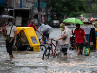 People wade through a flooded street following heavy rains in Manila,  Philippines, on July 21, 2021.(