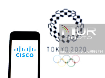 In this photo illustration a Cisco Systems, Inc. logo seen displayed on a smartphone with a Tokyo 2020 Olympic Games logo in the background....