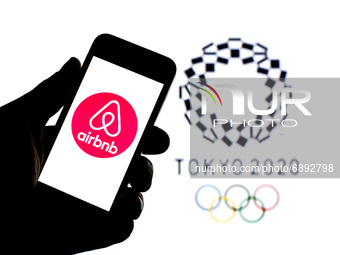 In this photo illustration a Airbnb, Inc. logo seen displayed on a smartphone with a Tokyo 2020 Olympic Games logo in the background. (