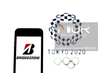 In this photo illustration a Bridgestone logo seen displayed on a smartphone with a Tokyo 2020 Olympic Games logo in the background. (
