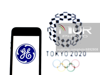 In this photo illustration a General Electric logo seen displayed on a smartphone with a Tokyo 2020 Olympic Games logo in the background. (