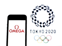 In this photo illustration a Omega SA logo seen displayed on a smartphone with a Tokyo 2020 Olympic Games logo in the background. (