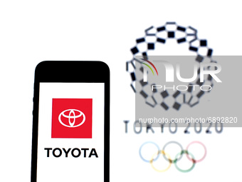 In this photo illustration a Toyota Motor Corporation logo seen displayed on a smartphone with a Tokyo 2020 Olympic Games logo in the backgr...