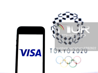 In this photo illustration a Visa Inc. logo seen displayed on a smartphone with a Tokyo 2020 Olympic Games logo in the background. (