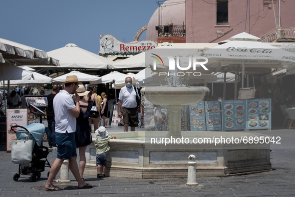 People are walking in the center of Chania, Greece during rising temperatures, passing next to the fountain on July 22, 2021.  