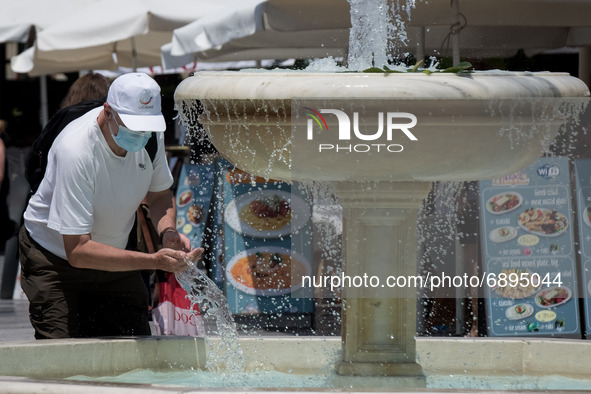 People are walking in the center of Chania, Greece during rising temperatures, passing next to the fountain on July 22, 2021.  