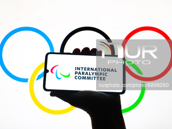 International Paralympic Committee logo is displayed on a mobile phone screen photographed with Olympic Rings symbol background for illustra...