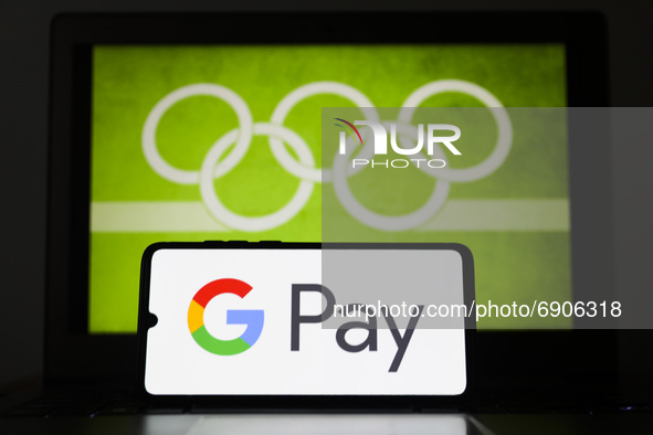 Google Pay logo is displayed on a mobile phone screen photographed with Olympic rings symbol on the background for illustration photo. Leszc...