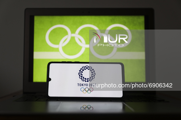 Tokyo Olympics 2020 logo is displayed on a mobile phone screen photographed with Olympic rings symbol on the background for illustration pho...