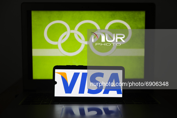 VISA card logo is displayed on a mobile phone screen photographed with Olympic rings symbol on the background for illustration photo. Leszcz...
