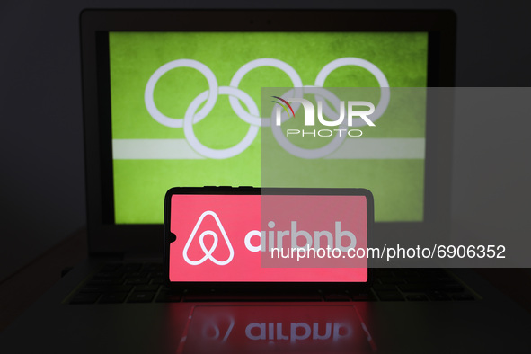 Airbnb logo is displayed on a mobile phone screen photographed with Olympic rings symbol on the background for illustration photo. Leszczewe...