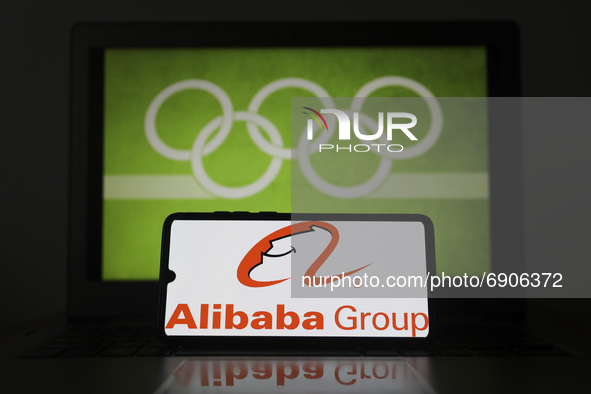 Alibaba Group logo is displayed on a mobile phone screen photographed with Olympic rings symbol on the background for illustration photo. Le...