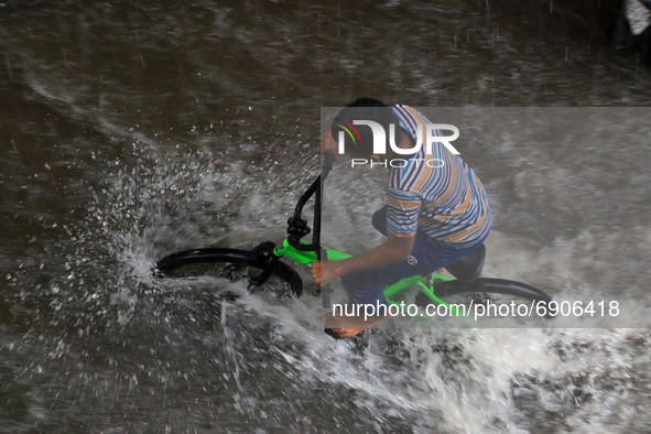 A boy ride bicycle on  waterlogged street during rain in Jaipur, Rajasthan, India, on July 26, 2021. 