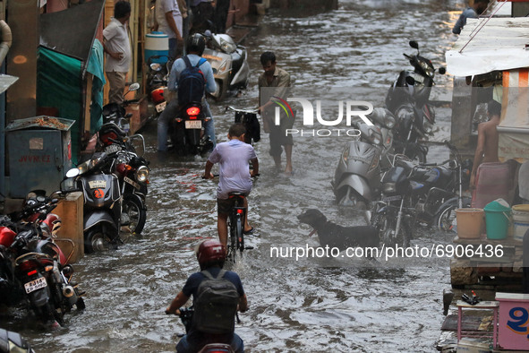 Commuters wade through a waterlogged street during rain in Jaipur, Rajasthan, India, on July 26, 2021. 