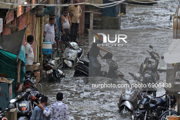 Commuters wade through a waterlogged street during rain in Jaipur, Rajasthan, India, on July 26, 2021. 