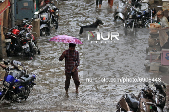 A commuter wade through a waterlogged street during rain in Jaipur, Rajasthan, India, on July 26, 2021. 