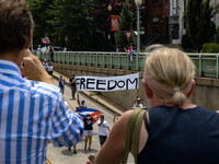 People watch as demonstrators march under an overpass during a demonstration for Cuban rights in Washington, D.C. on July 26, 2021 (