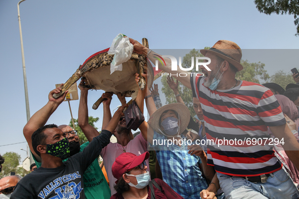 Supporters of Kais Saied chant slogans against the islamist party Ennahdha as they lift a chair during a demonstration held in front of the...