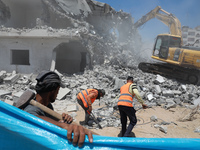 Palestinian workers clear the rubble of buildings, leveled by Israeli bombing during the conflict between Israel and Hamas in May this year,...