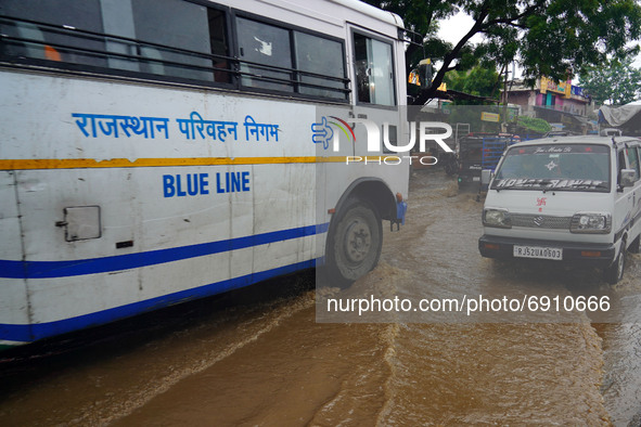 Indian People drives past a flooded street after heavy monsoon rains in Ajmer, Rajasthan, India on 27 July 2021.  