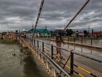 A man holds an Umbrella as he walks over a bridge during rainfall in Sopore, District Baramulla Jammu And Kashmir, India on 28 July 2021. 4...